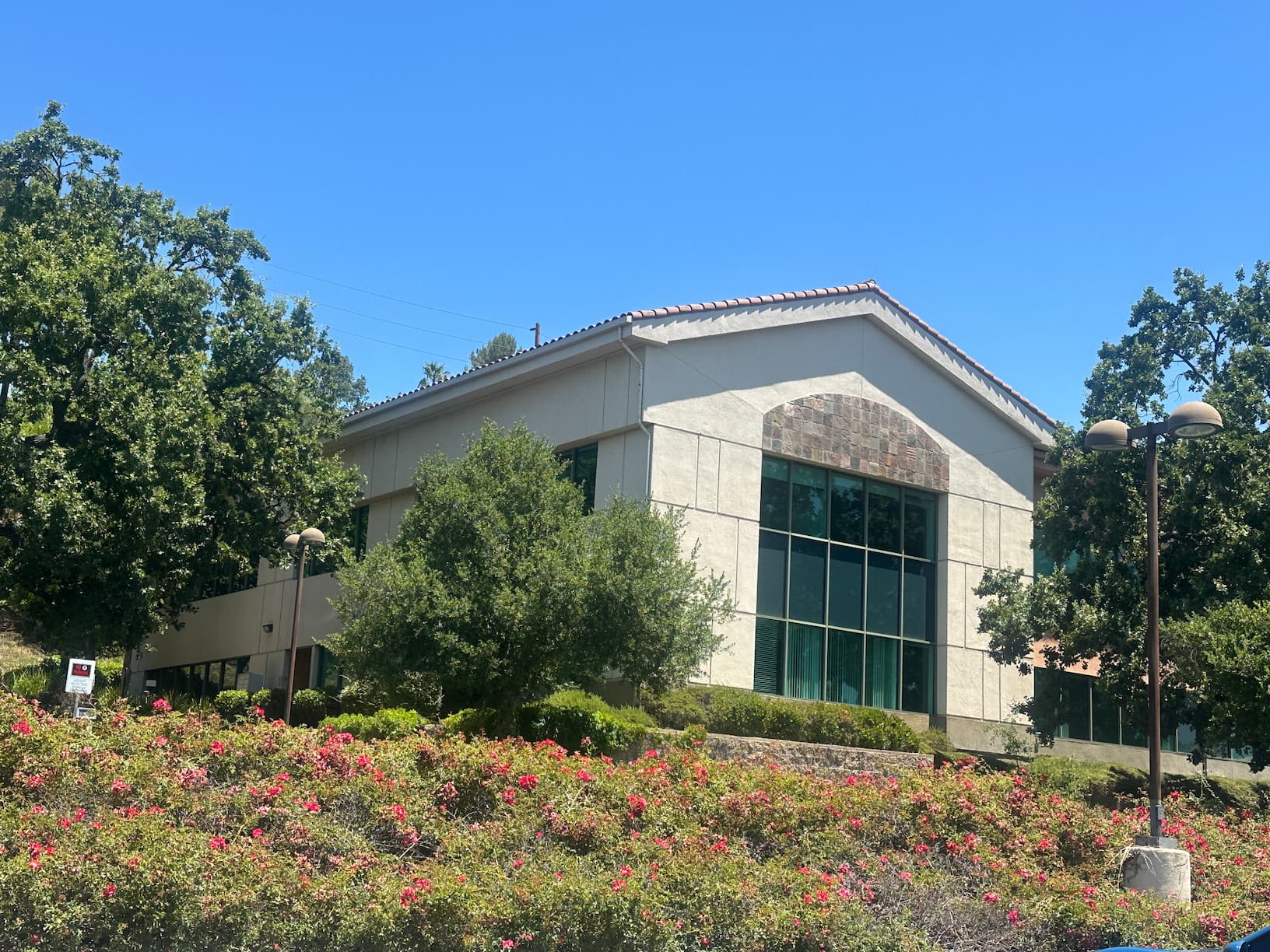 Exterior of the Moonglade Recovery facility building with tall windows, trees, and flowering landscaping